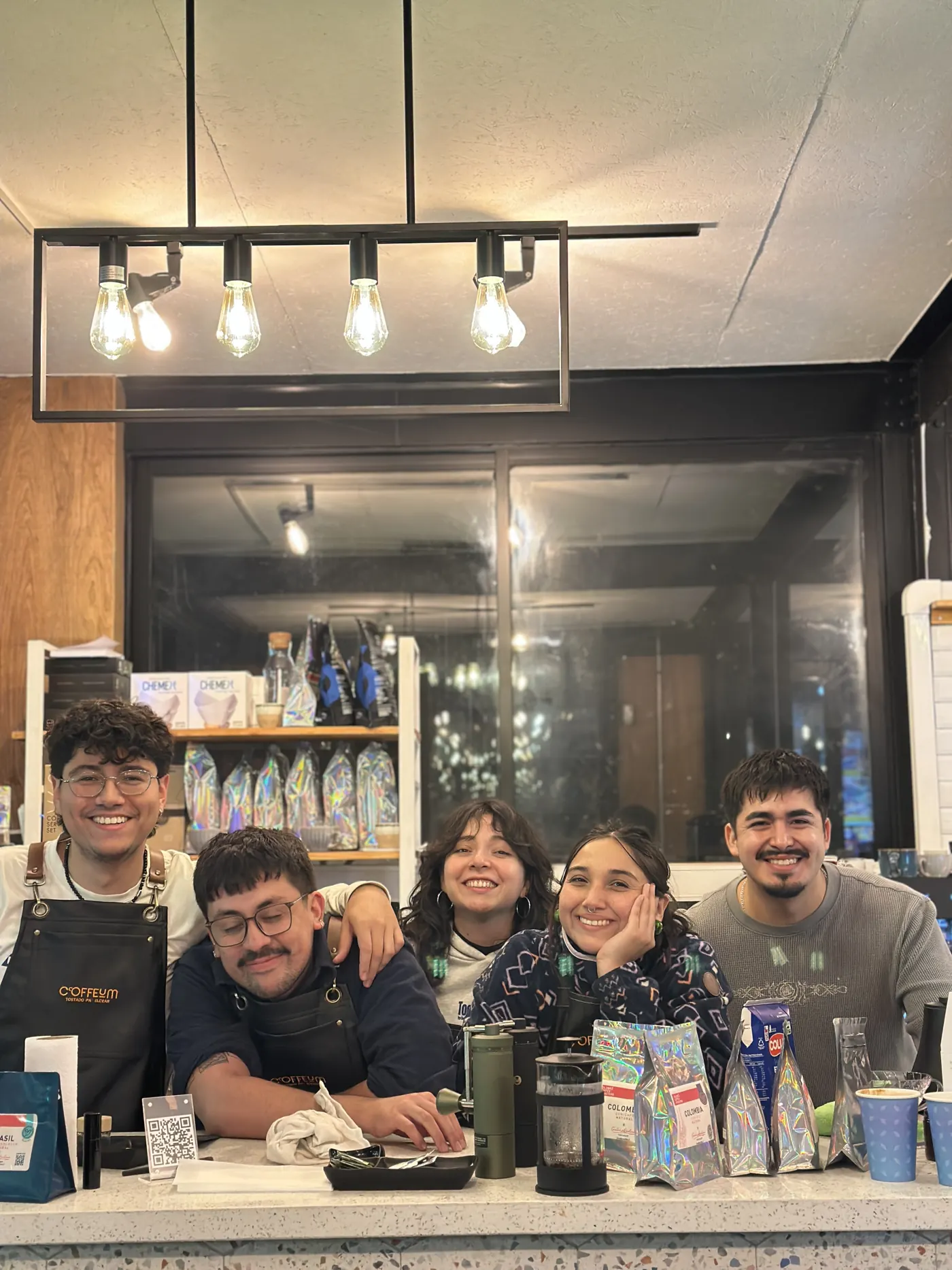 Equipo de baristas de Coffeum sonriendo en la barra de la cafetería en Barrio Italia